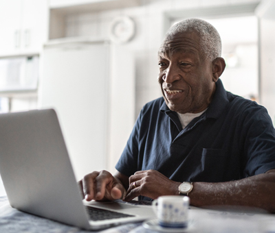 Older man smiling typing on keyboard