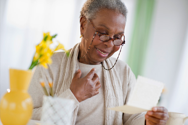 An older woman smiling while reading a card
